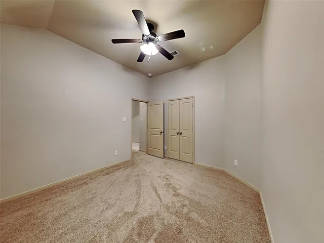 an empty room with chandelier fan and windows
