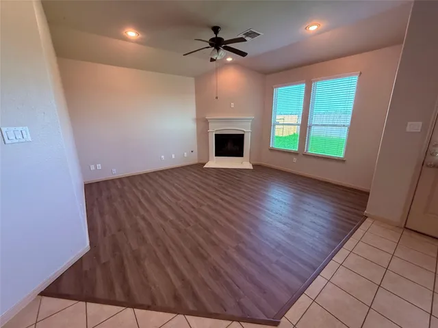 an empty room with windows a fireplace and a chandelier fan