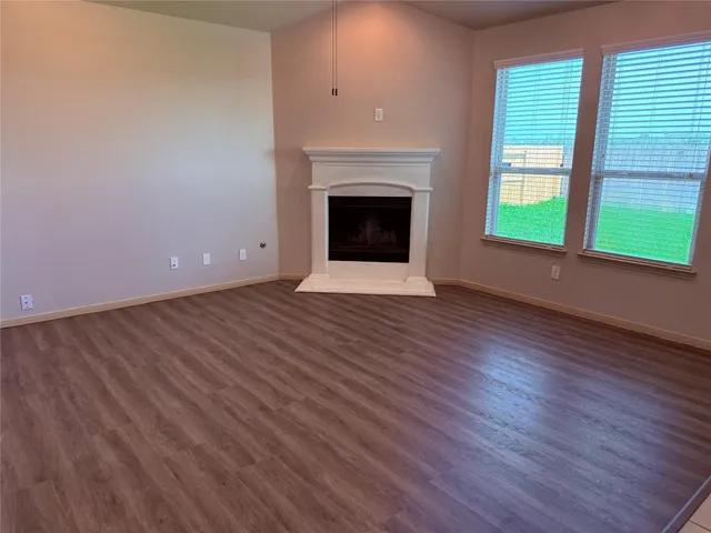 an empty room with wooden floor fireplace and windows