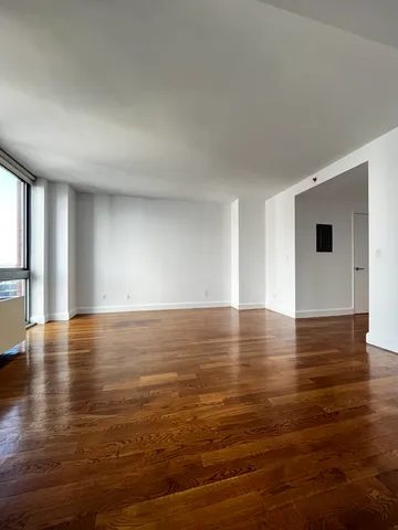 a view of empty room with wooden floor and windows