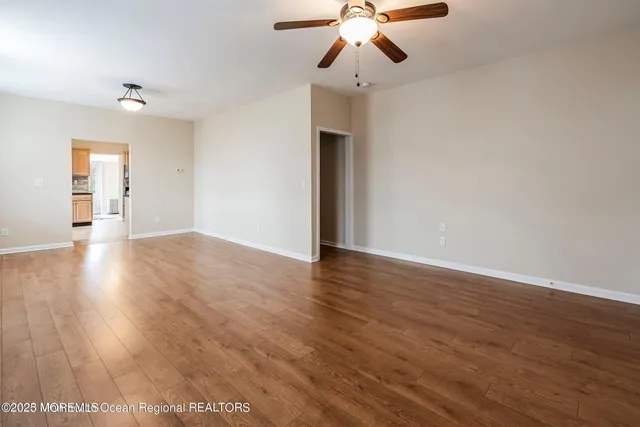 a view of an empty room with wooden floor and chandelier
