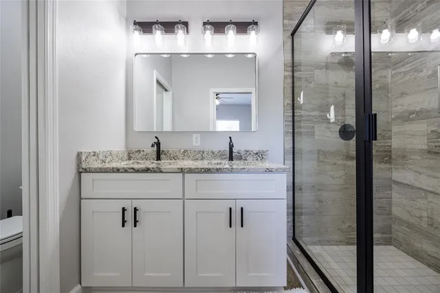 a bathroom with a granite countertop sink mirror and shower