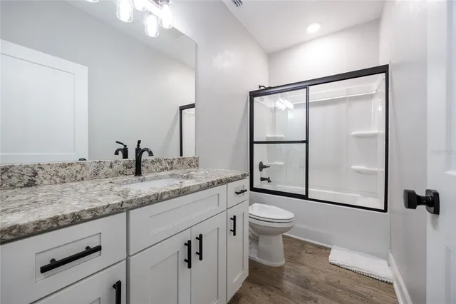 a bathroom with a granite countertop toilet a sink and a window