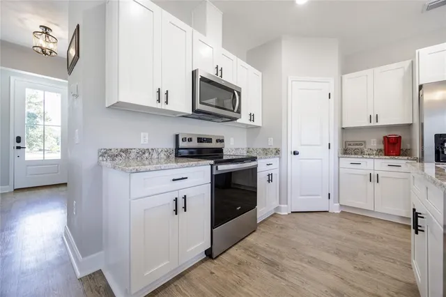 a kitchen with white cabinets and refrigerator