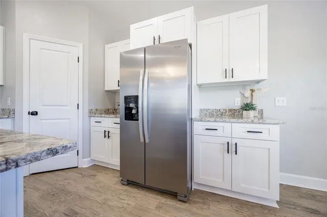 a kitchen with a stove a sink a kitchen island with chairs and wooden floor
