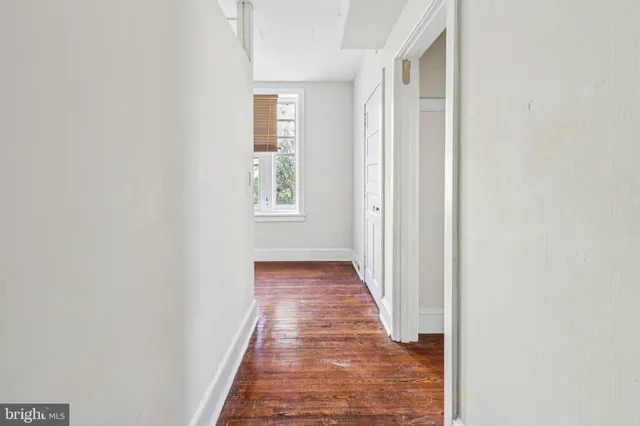 a view of a hallway with wooden floor and a window