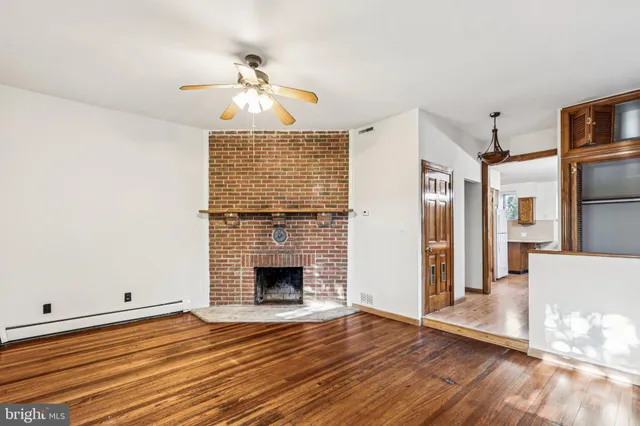 a view of an empty room with wooden floor fireplace and a window