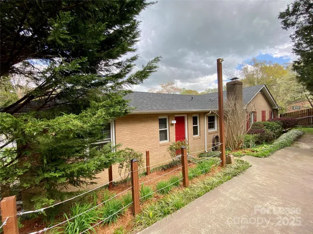 a view of a backyard with potted plants and large trees