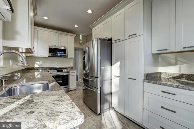 a kitchen with granite countertop a stove a sink and a refrigerator