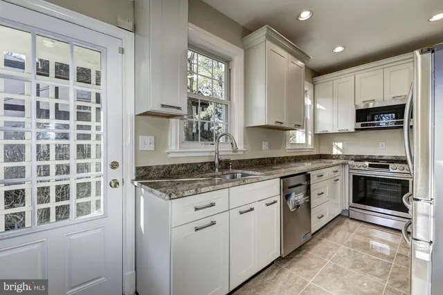 a kitchen with stainless steel appliances granite countertop a sink stove and cabinets