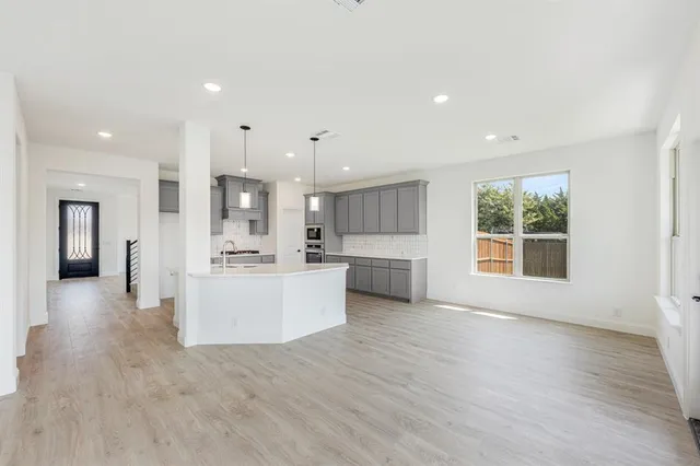 a view of a kitchen with kitchen island wooden floors wooden cabinets counter space and a window