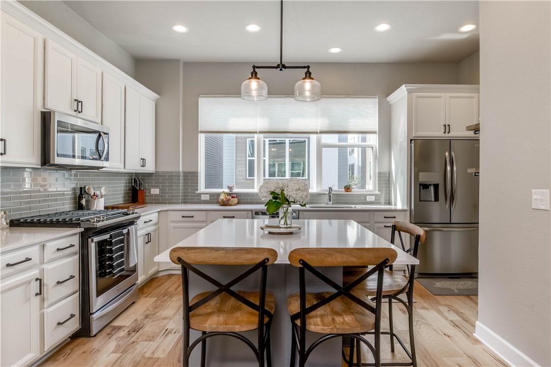 a kitchen with stainless steel appliances granite countertop a stove a refrigerator a kitchen island a dining table and chairs