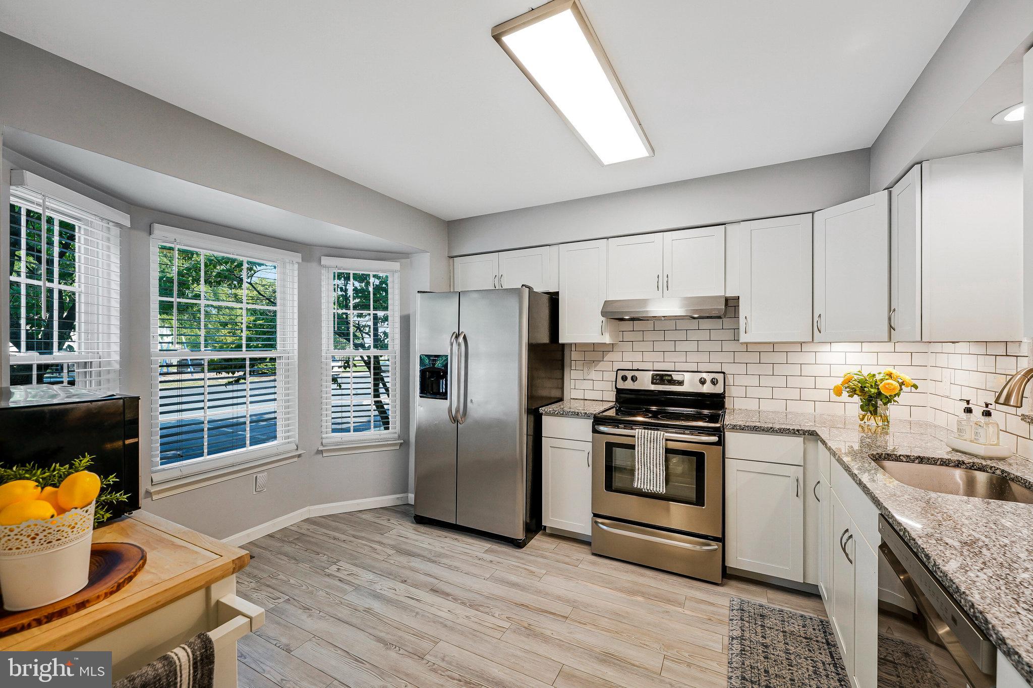 1085 Smartts Lane Northeast Leesburg, VA 20176 - Photo 7 of 38 a kitchen with stainless steel appliances granite countertop a stove a refrigerator a sink a dining table and chairs
