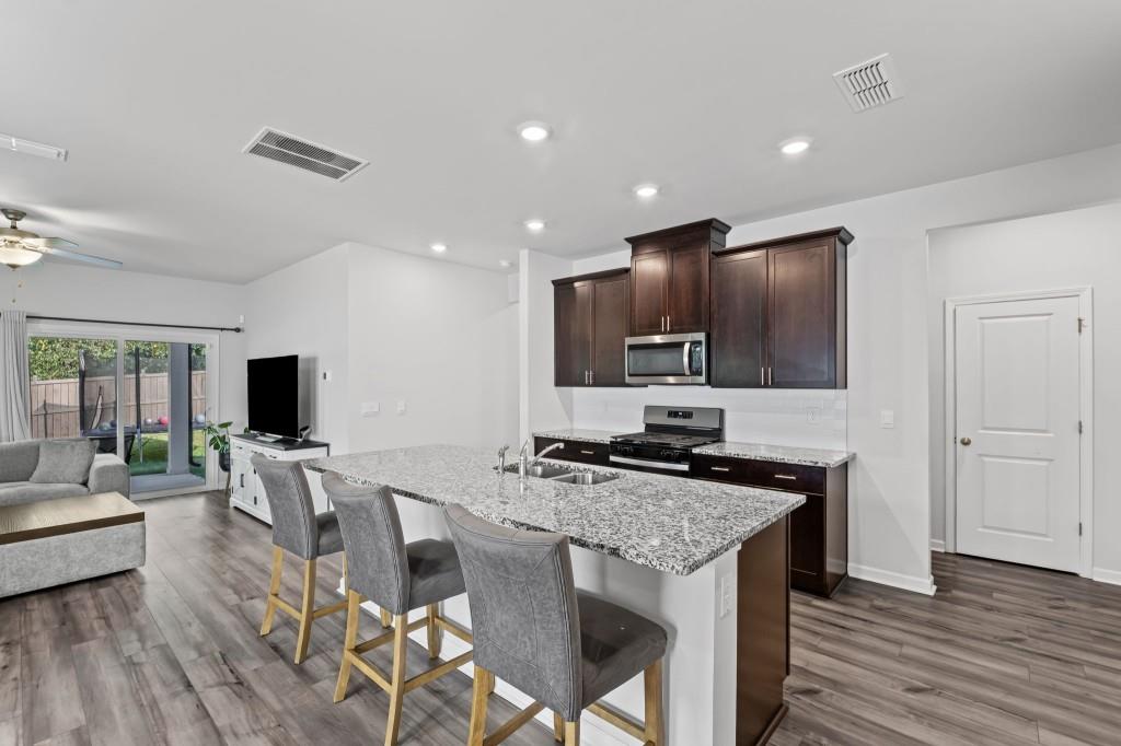 346 Wells Circle Canton, GA 30114 - Photo 12 of 35 a kitchen with stainless steel appliances granite countertop a stove top oven a sink dishwasher a dining table and chairs with wooden floor