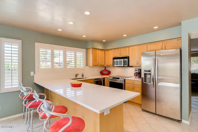 a kitchen with stainless steel appliances kitchen island granite countertop a refrigerator and a sink