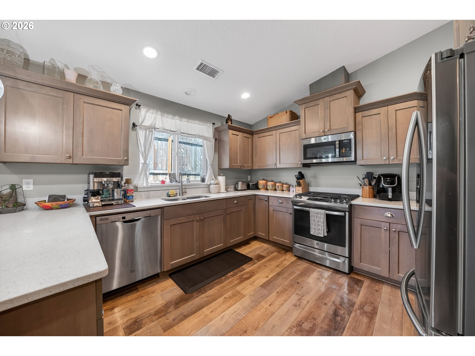 601 Southeast Rose Ridge Drive Winston, OR 97496 - Photo 10 of 40 a kitchen with kitchen island granite countertop a refrigerator oven a sink dishwasher and white cabinets with wooden floor