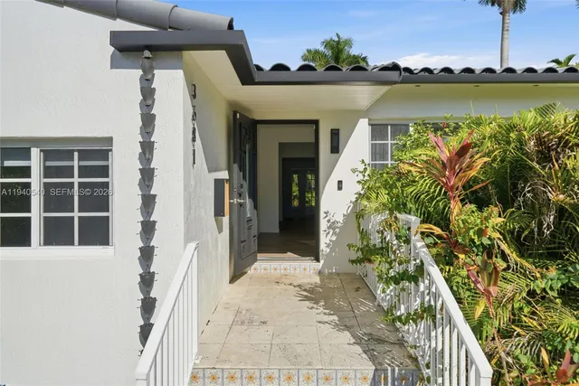 a front view of a house with a yard and potted plants
