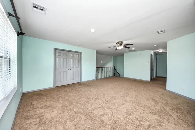 a view of a bedroom with a chandelier fan and windows