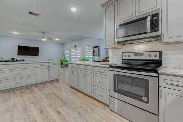 a kitchen with stainless steel appliances white cabinets a sink and a stove