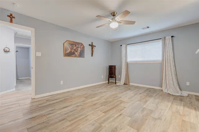 an empty room with wooden floor and ceiling fan