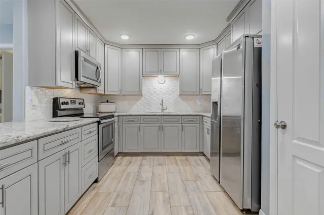 a kitchen with stainless steel appliances a refrigerator sink and white cabinets