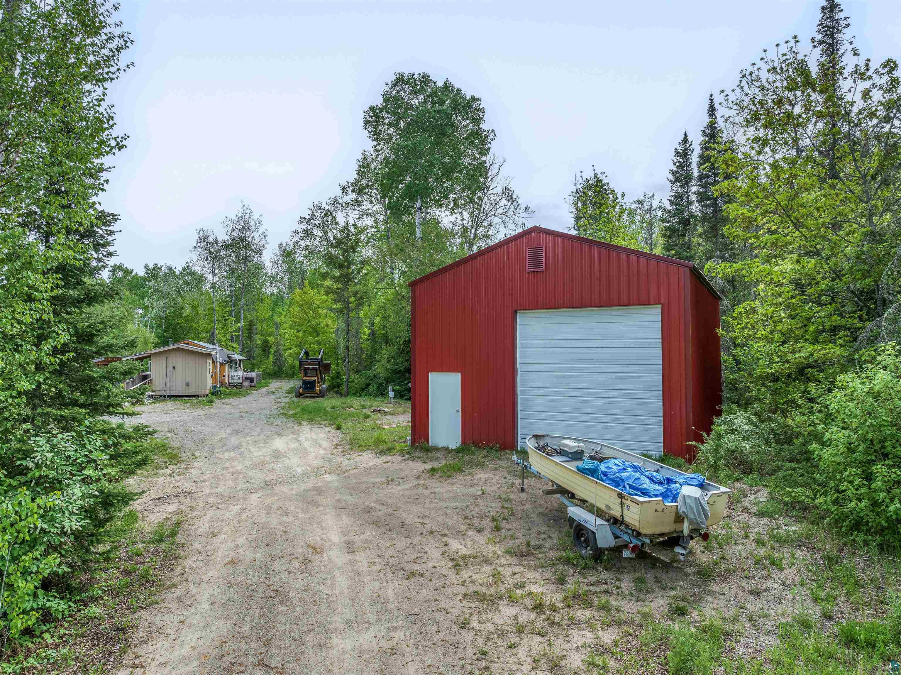 1152 Fernberg Road Ely, MN 55731 - Photo 2 of 24 Red metal utility building with a white roll-up garage door and an entry door