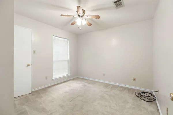 an empty room with windows and fan