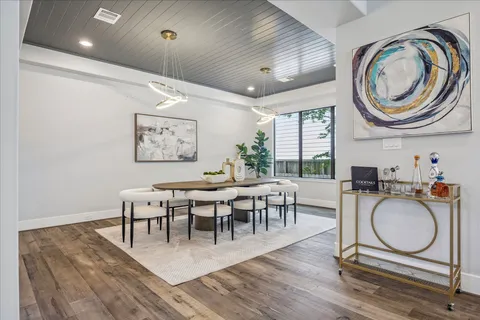 a dining room with wooden floor a chandelier a wooden table and chairs