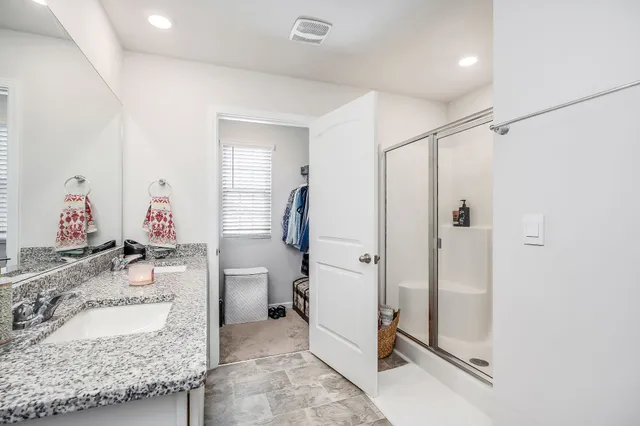 a en suite bathroom with a granite countertop sink mirror and a shower