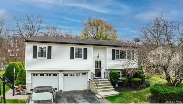 a view of a white house with a big yard and potted plants