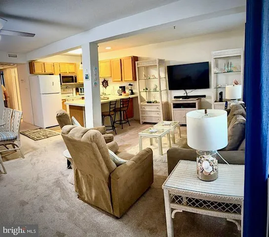 a living room with furniture a flat screen tv and a view of kitchen