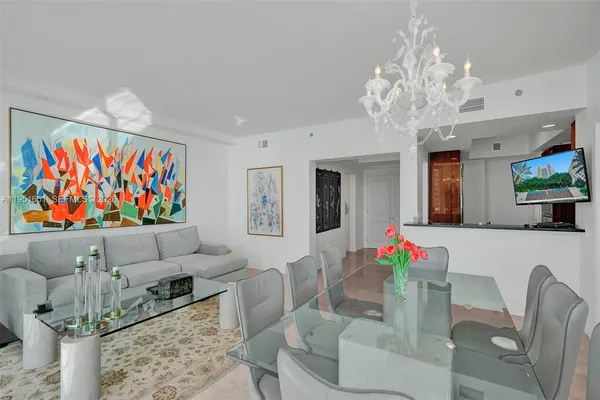 a living room with furniture a chandelier and a flat screen tv