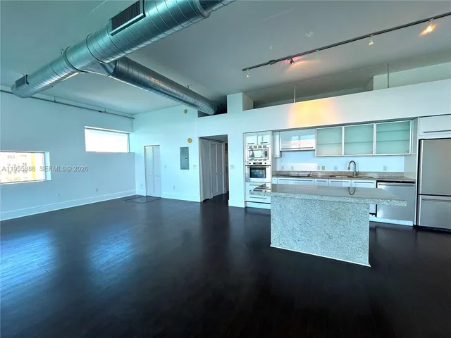 a kitchen with stainless steel appliances wooden floors and view living room