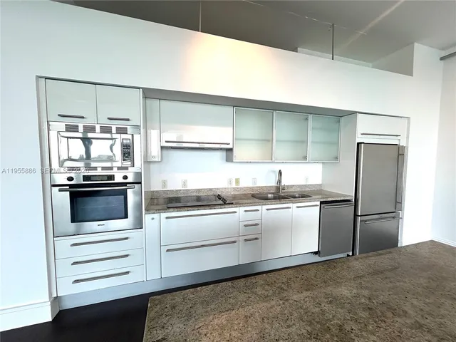 a kitchen with stainless steel appliances granite countertop a refrigerator and a stove top oven