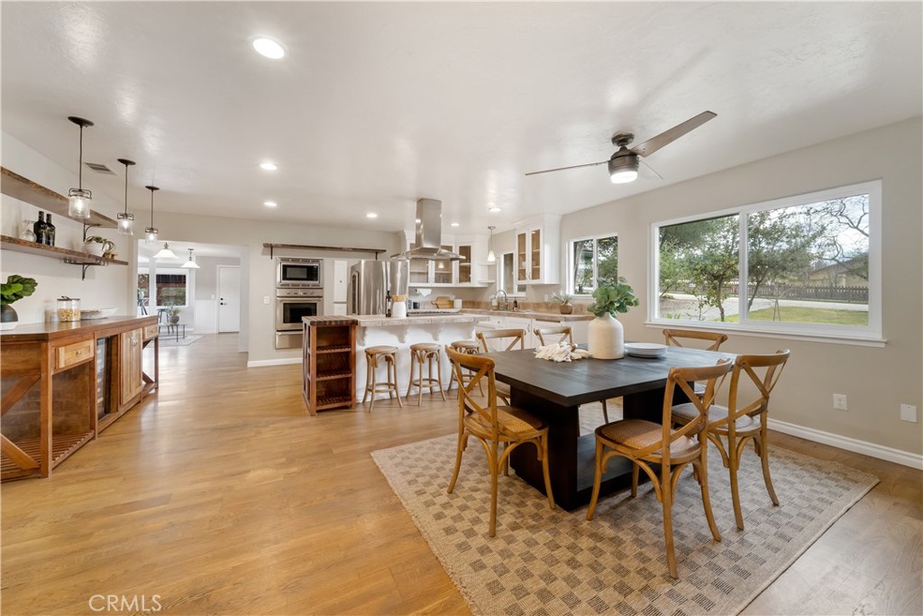 a dining area with stainless steel appliances kitchen island granite countertop a table chairs and a living room view