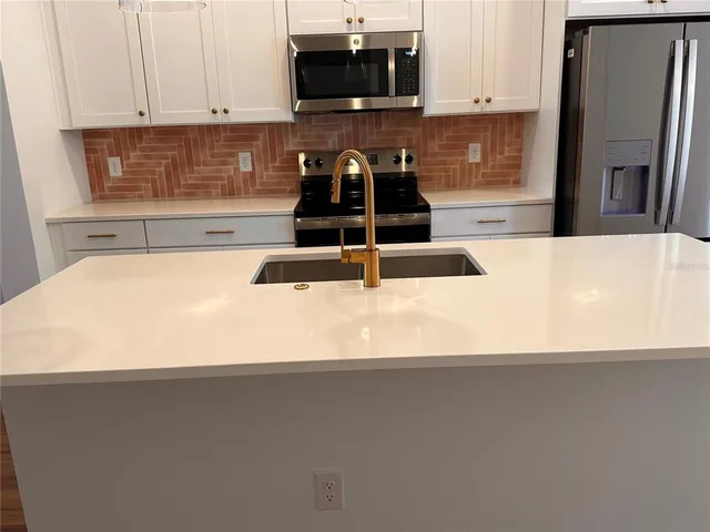 a kitchen with granite countertop a refrigerator and a stove top oven