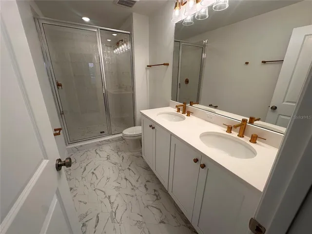 a bathroom with a double vanity sink mirror and shower