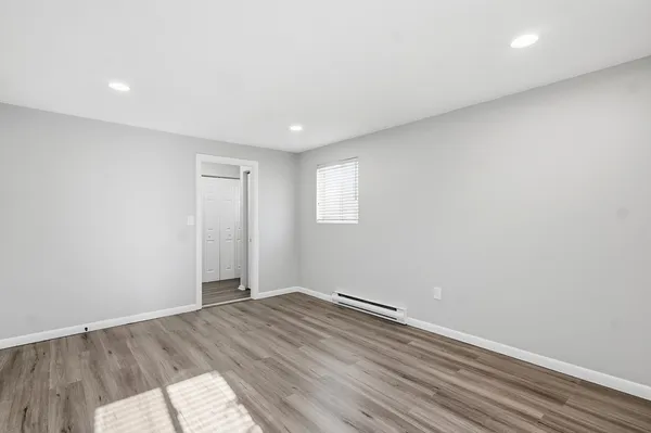an empty room with wooden floor and window