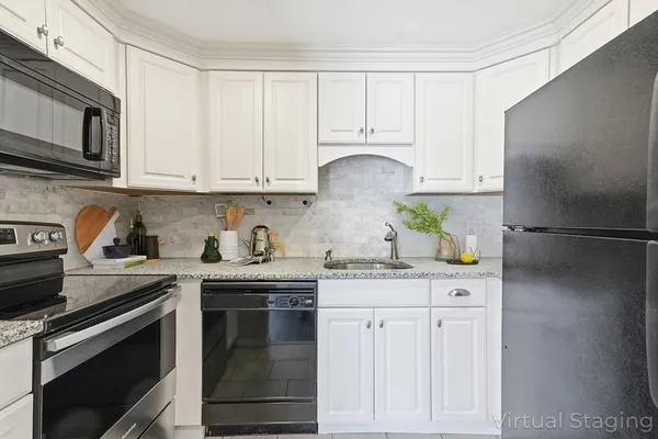 a kitchen with granite countertop white cabinets and stainless steel appliances