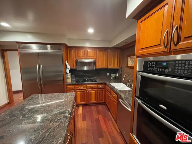 a kitchen with granite countertop stainless steel appliances and wooden cabinets