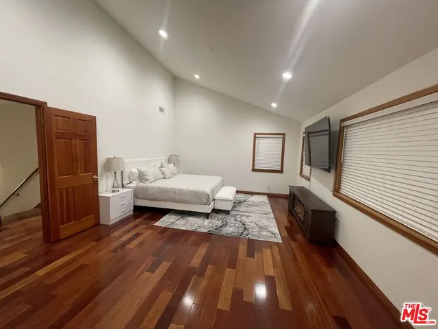 a spacious bedroom with a bed and a flat screen tv