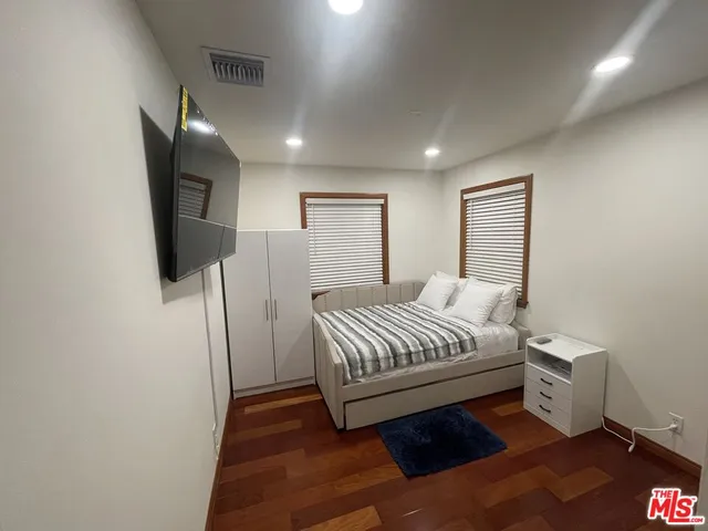 a spacious bedroom with a bed and a flat screen tv