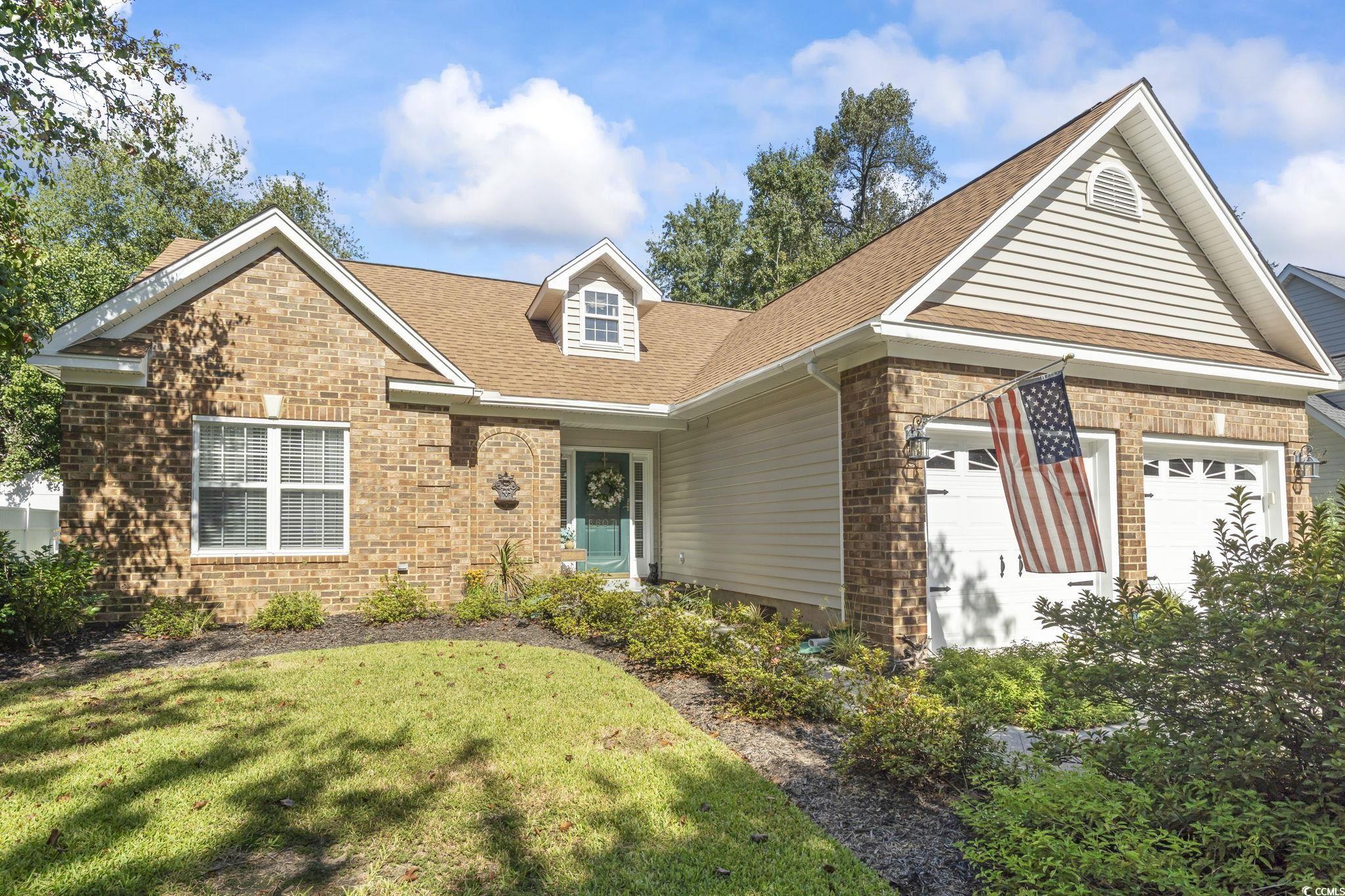 View of front facade featuring roof with shingles, brick siding, a garage, and a front yard