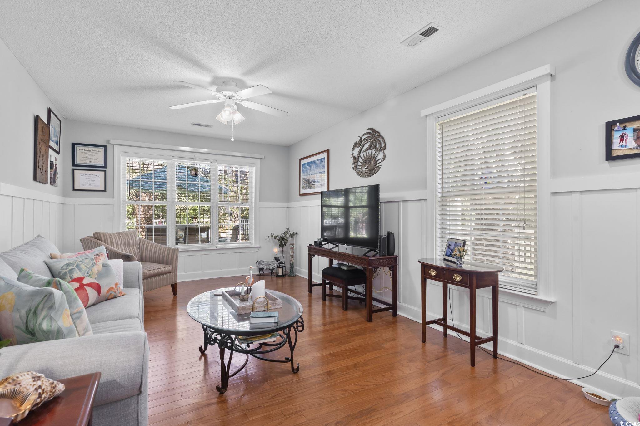3607 Brampton Drive Myrtle Beach, SC 29588 - Photo 22 of 34 Living area featuring a ceiling fan, wood finished floors, a textured ceiling, wainscoting, and a decorative wall
