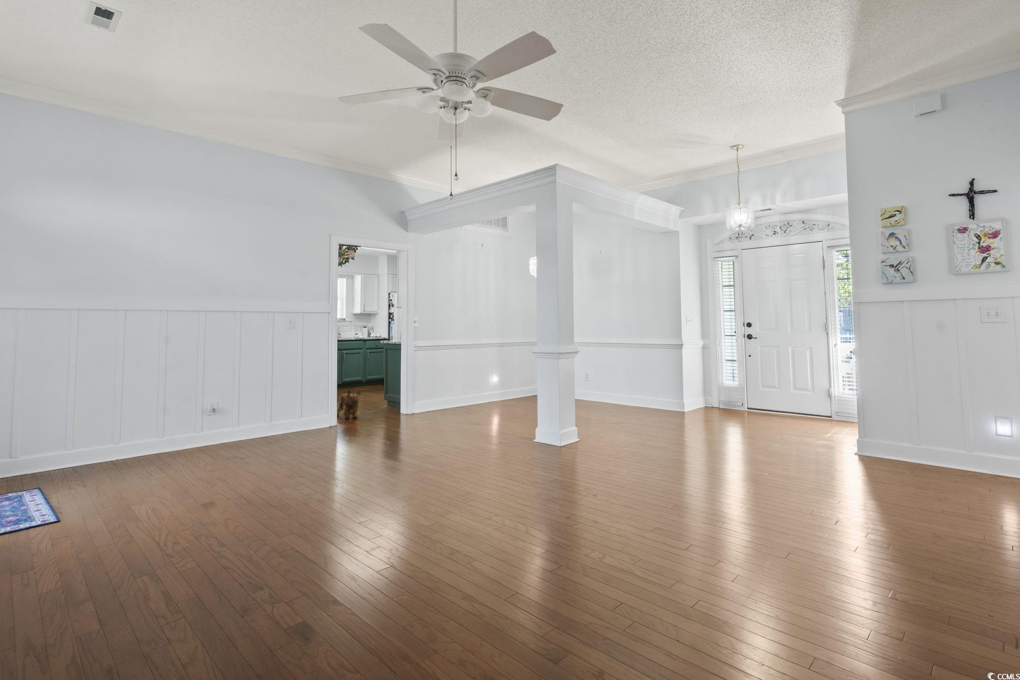 3607 Brampton Drive Myrtle Beach, SC 29588 - Photo 4 of 34 Unfurnished living room with wainscoting, a decorative wall, hardwood / wood-style floors, crown molding, and a ceiling fan