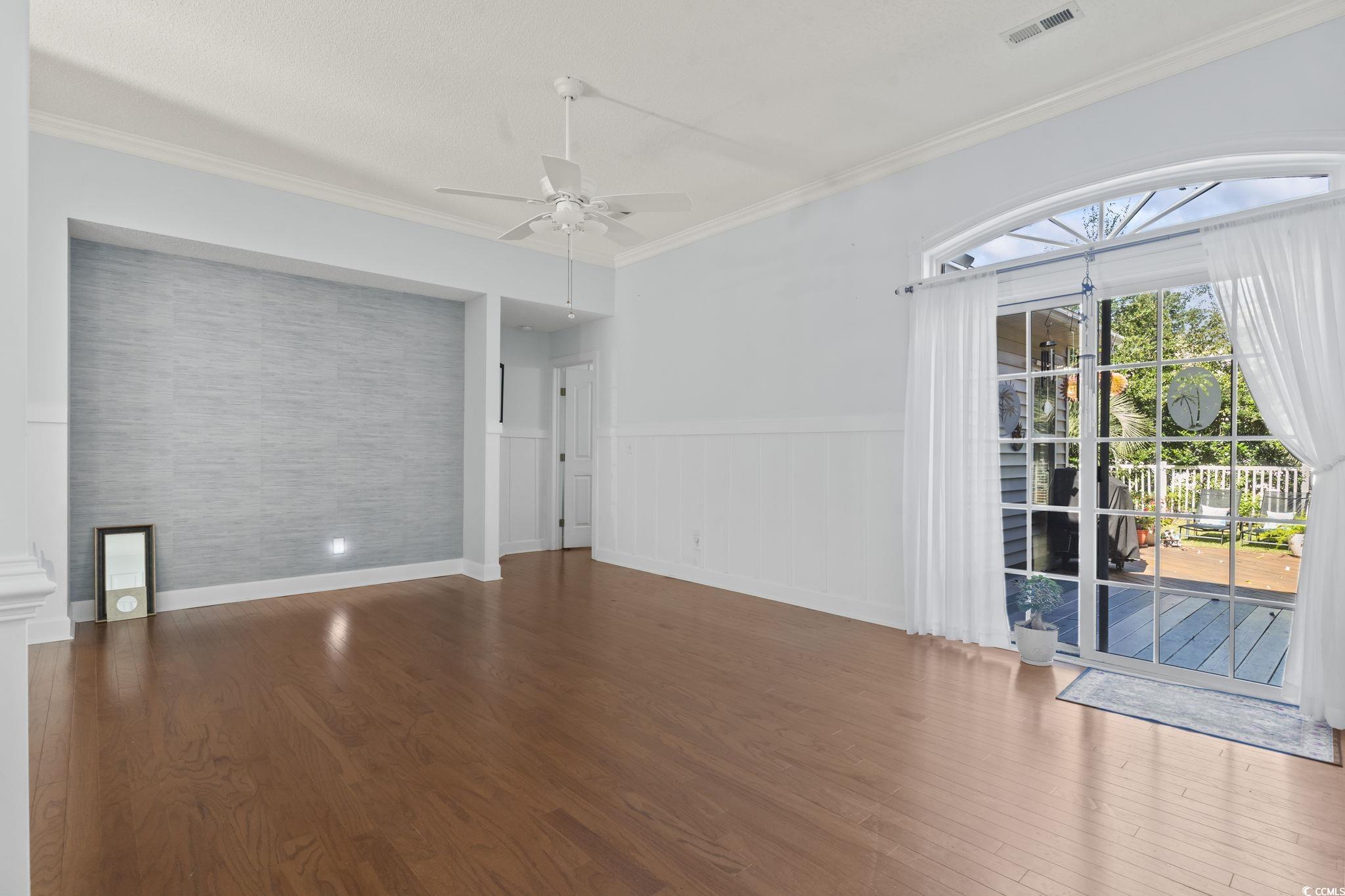 3607 Brampton Drive Myrtle Beach, SC 29588 - Photo 6 of 34 Empty room featuring ornamental molding, wood finished floors, ceiling fan, and wainscoting