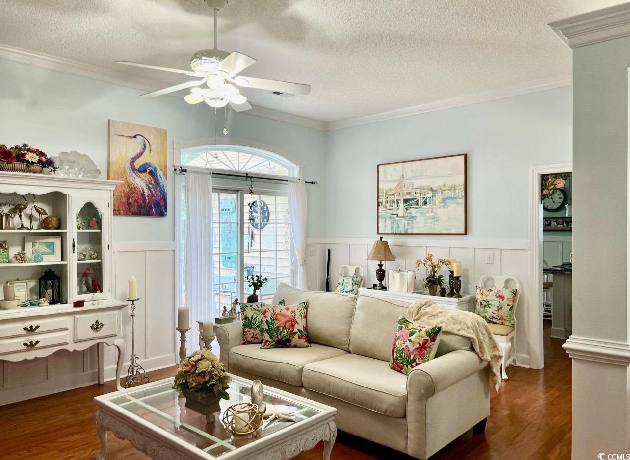 3607 Brampton Drive Myrtle Beach, SC 29588 - Photo 8 of 34 Living area featuring a textured ceiling, wainscoting, dark wood-type flooring, crown molding, and a decorative wall