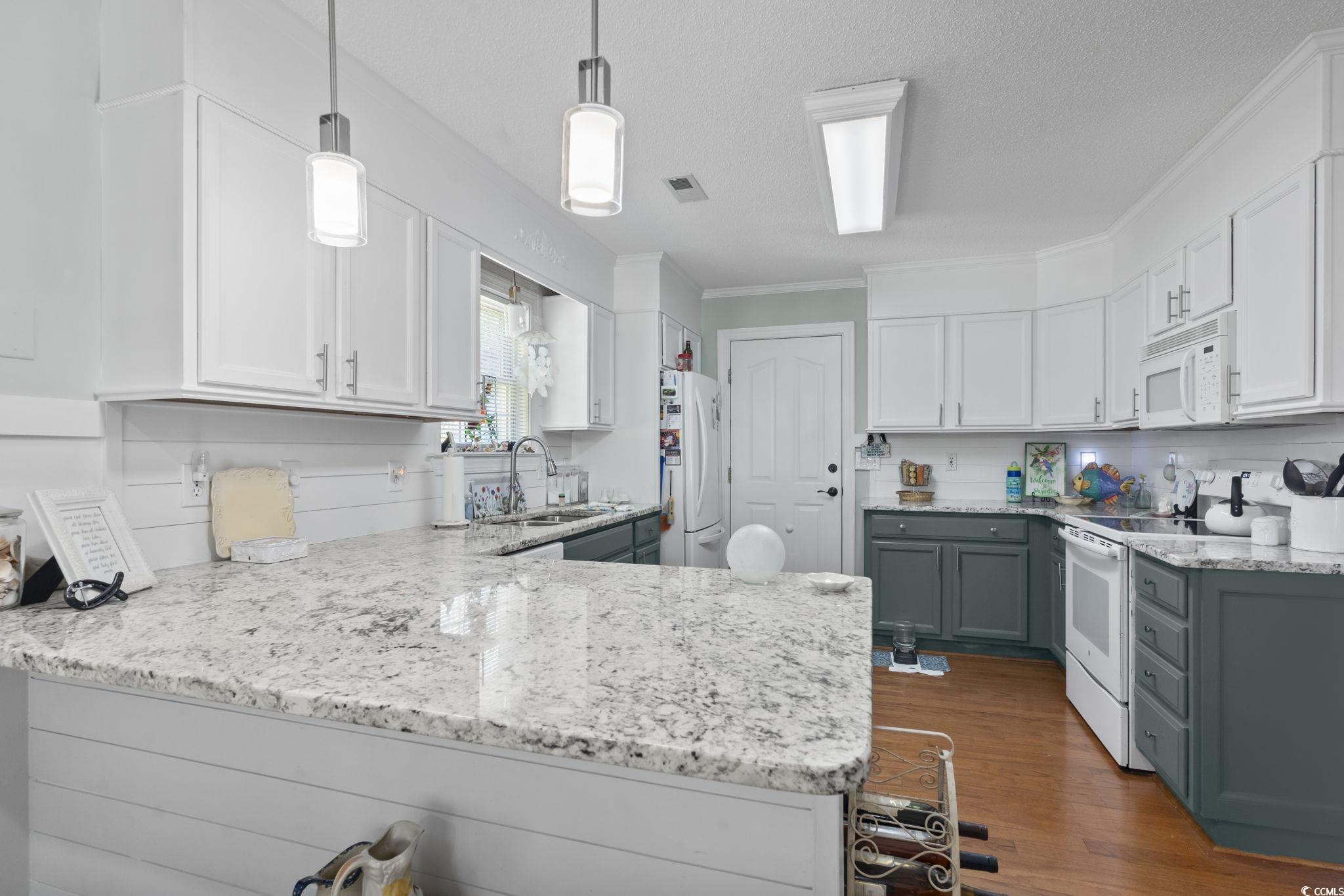3607 Brampton Drive Myrtle Beach, SC 29588 - Photo 10 of 34 Kitchen featuring white cabinets, white appliances, light stone counters, decorative light fixtures, and crown molding