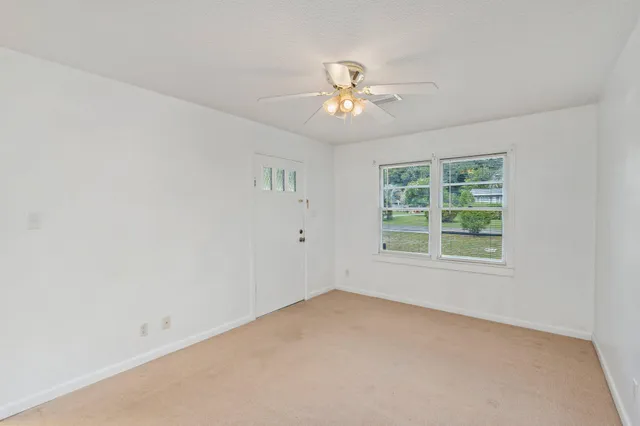 an empty room with a window and a fan