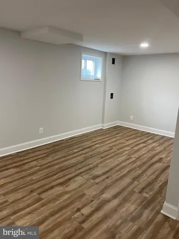 a view of an empty room with wooden floor and windows